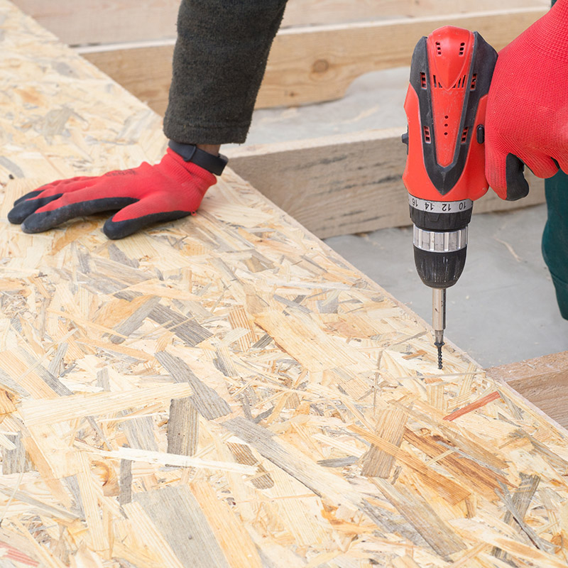 Man worker screws wooden oriented stands bords on insulated floo